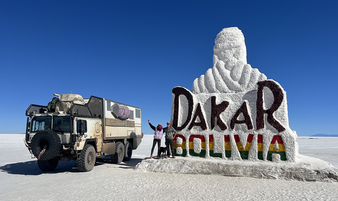 Wüste mit Hymer Camper davor ein Mann der einem Kamel in das Gesicht schaut, Nase an Nase, Peter Ocker, Weltenbummler Treffen